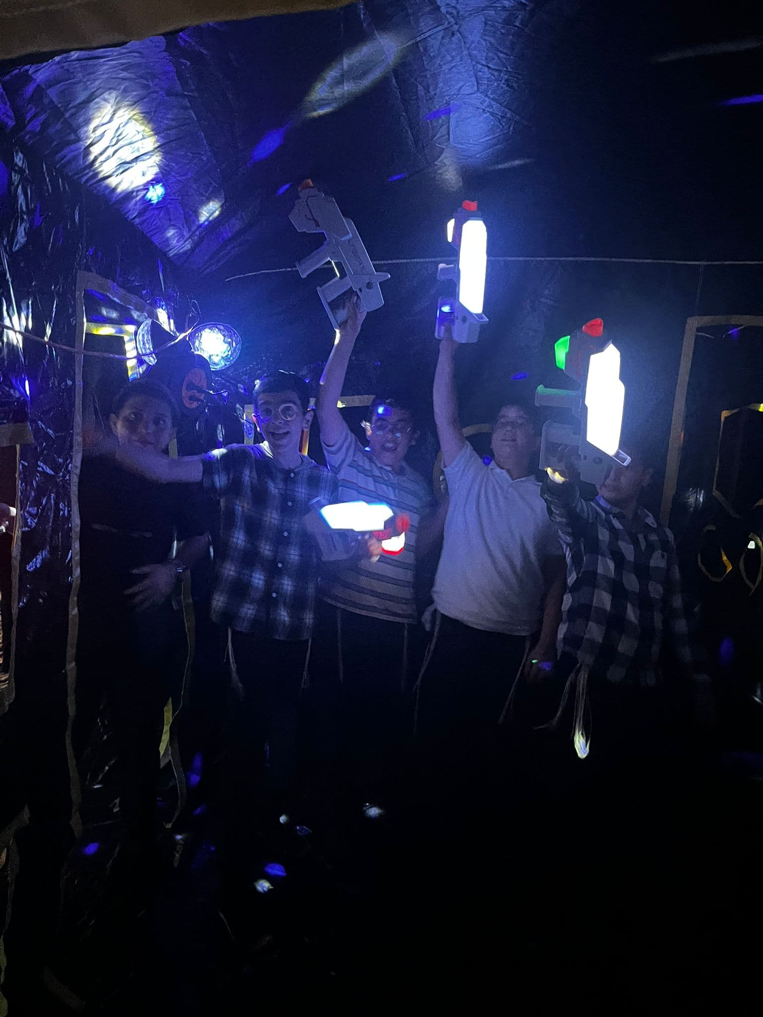 קבוצת ילדים מרימה רובי לייזר מוארים בסיום קרב קבוצתי